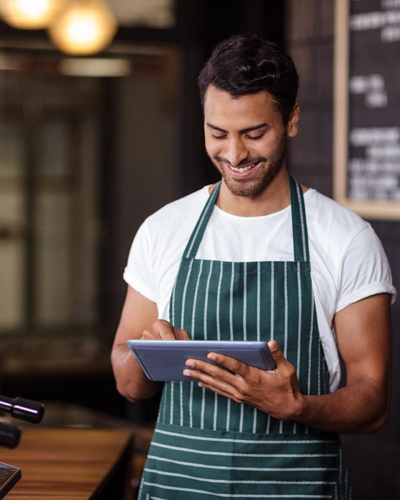 smiling-barista-using-tablet-in-the-bar-PPES8JB.jpg